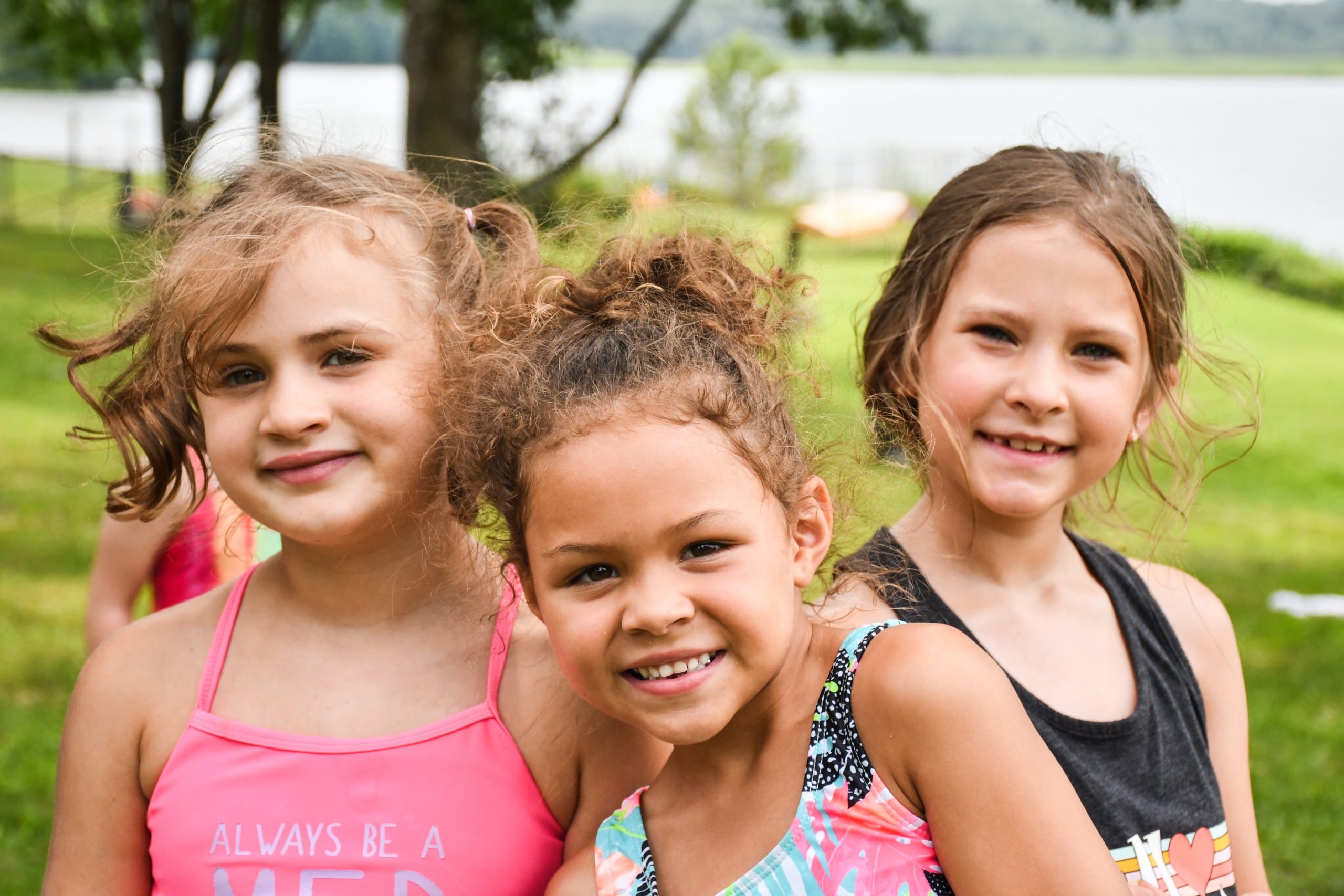 Three school age campers smiling while enjoying time outside at Presque Isle State Park